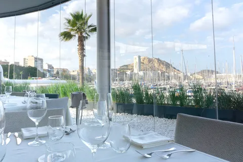 Una mesa puesta en la terraza de Panoramis, con una palmera y el castillo detrás