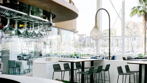 La barra de la terraza de Dársena, con las copas colgadas y el puerto al fondo